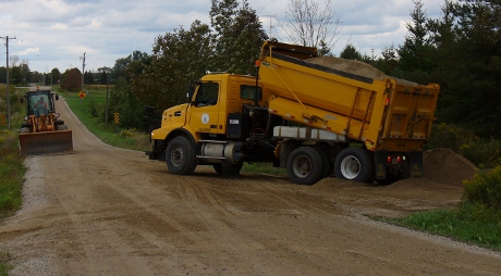 Dump truck and bulldozer adding stone chip surface to trail